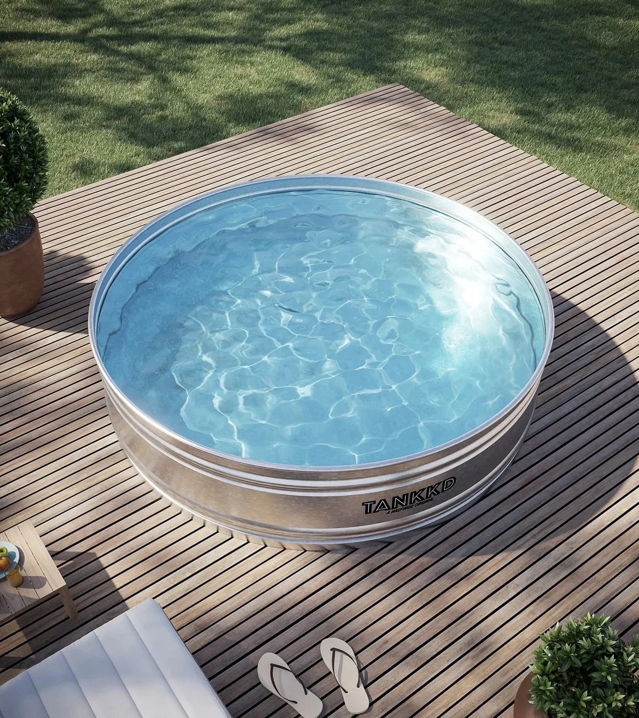 An outdoor circular hot tub filled with water on a wooden deck, with potted plants and furniture nearby.