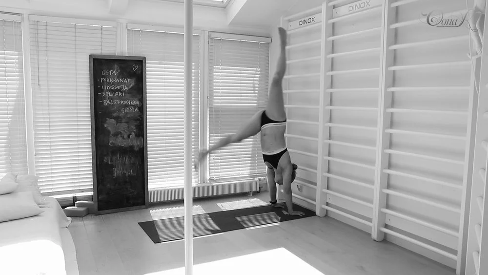 Pole dancer kicking into handstand.