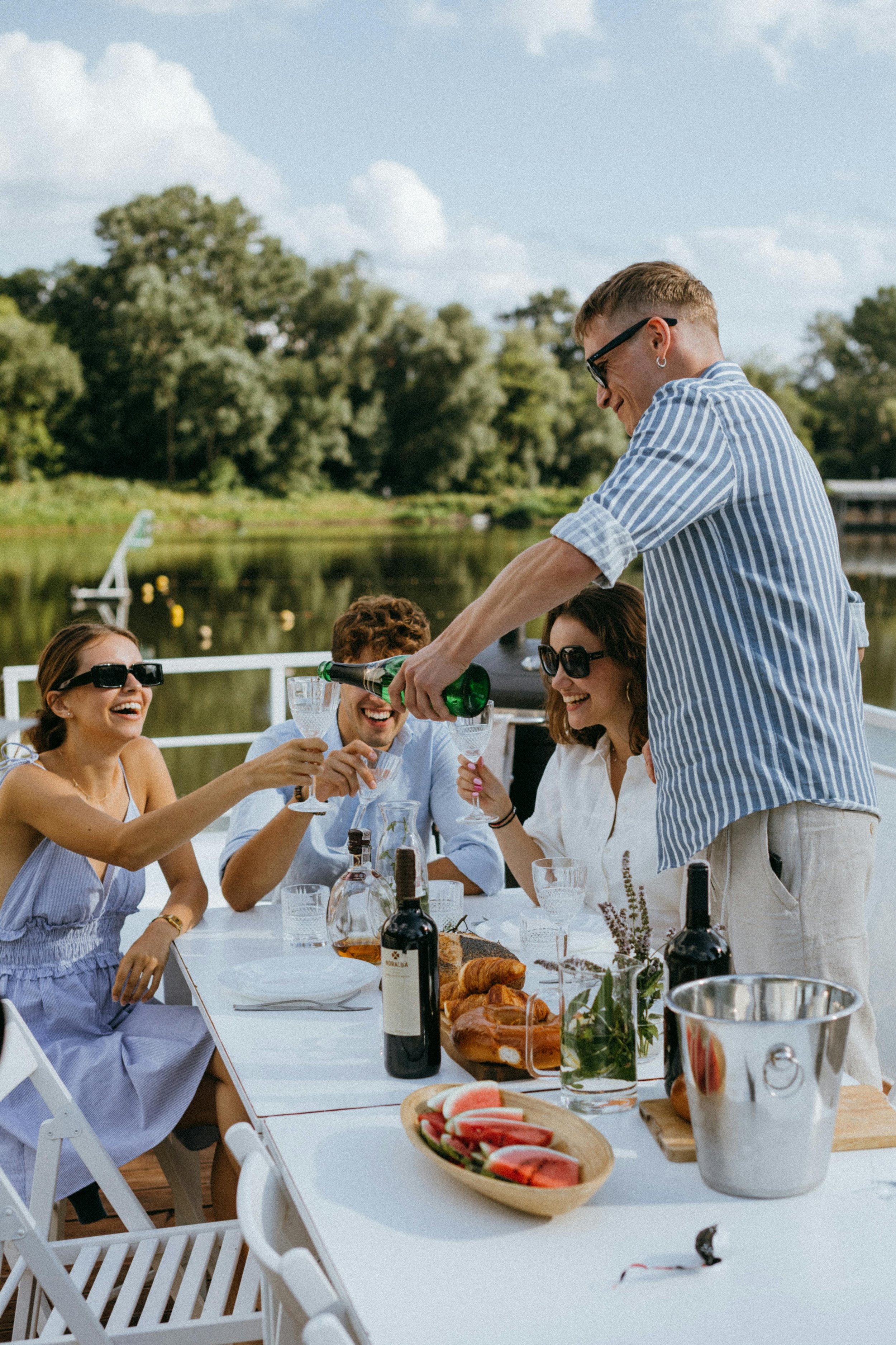 Grupp människor som njuter av en måltid och dryck en sommardag på restaurangen The Fairway på Motala Golfklubb.