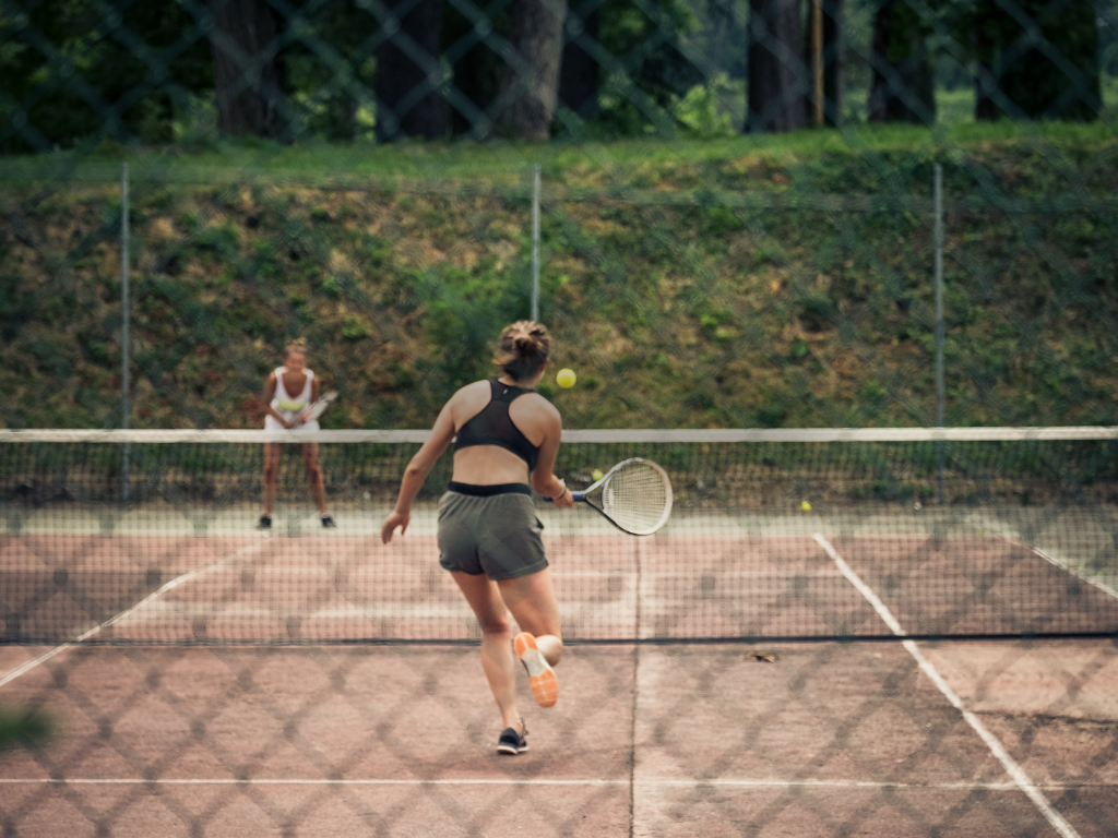 Twee vrouwen spelen tennis op een tennisveld 