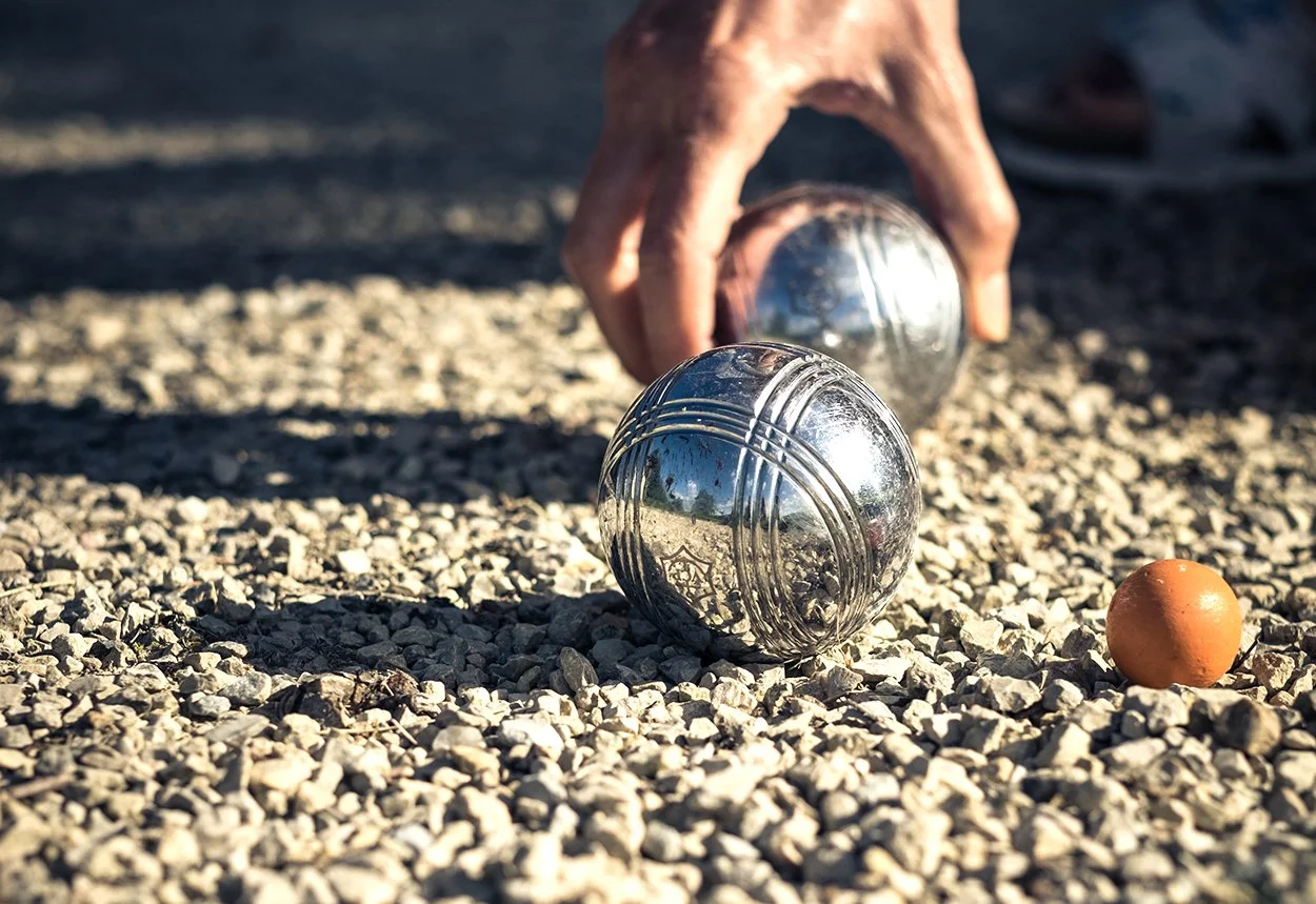 Een hand die een petanquebal opraapt