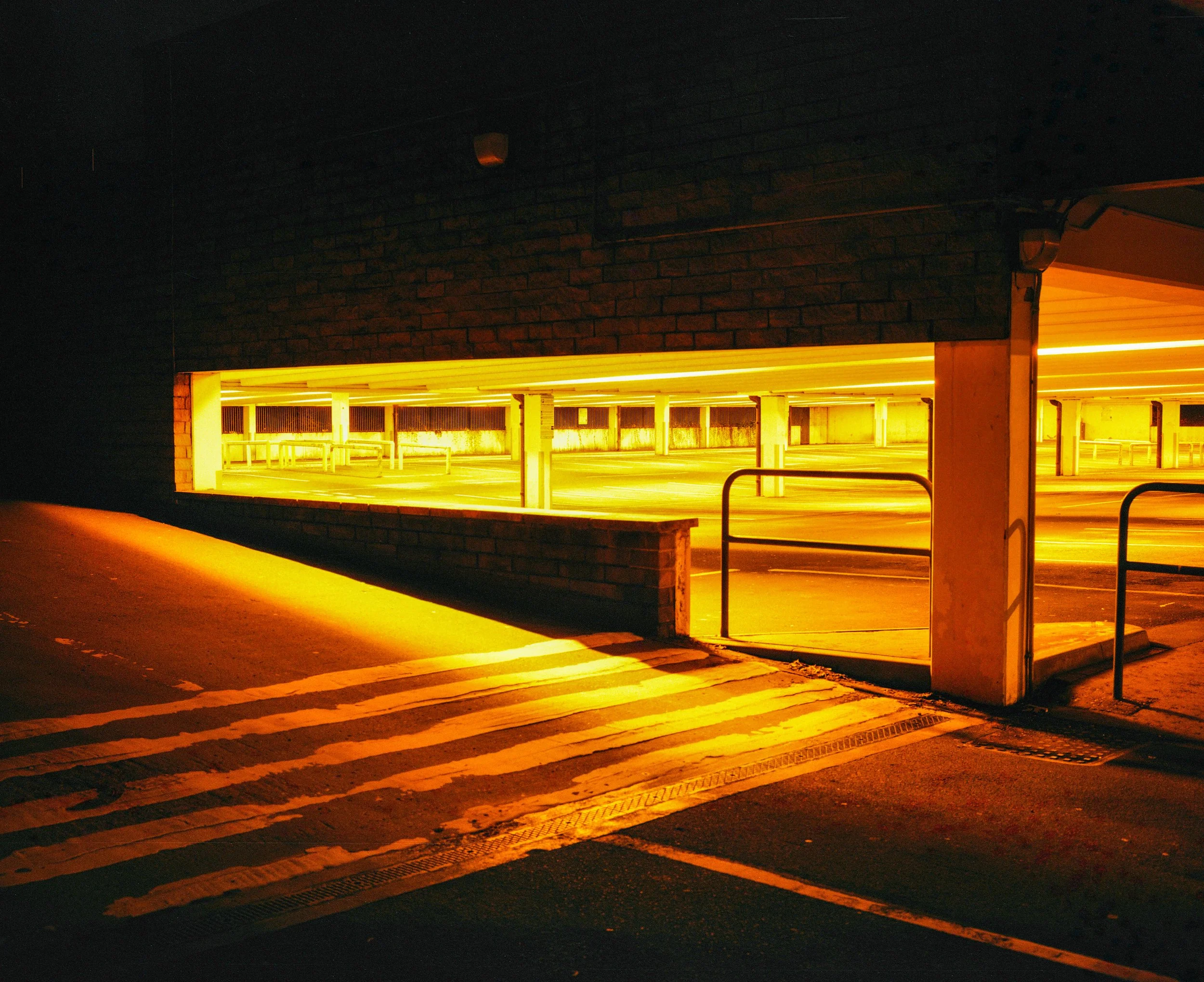 Dark parking garage with yellow lighting and striped pedestrian crosswalks.