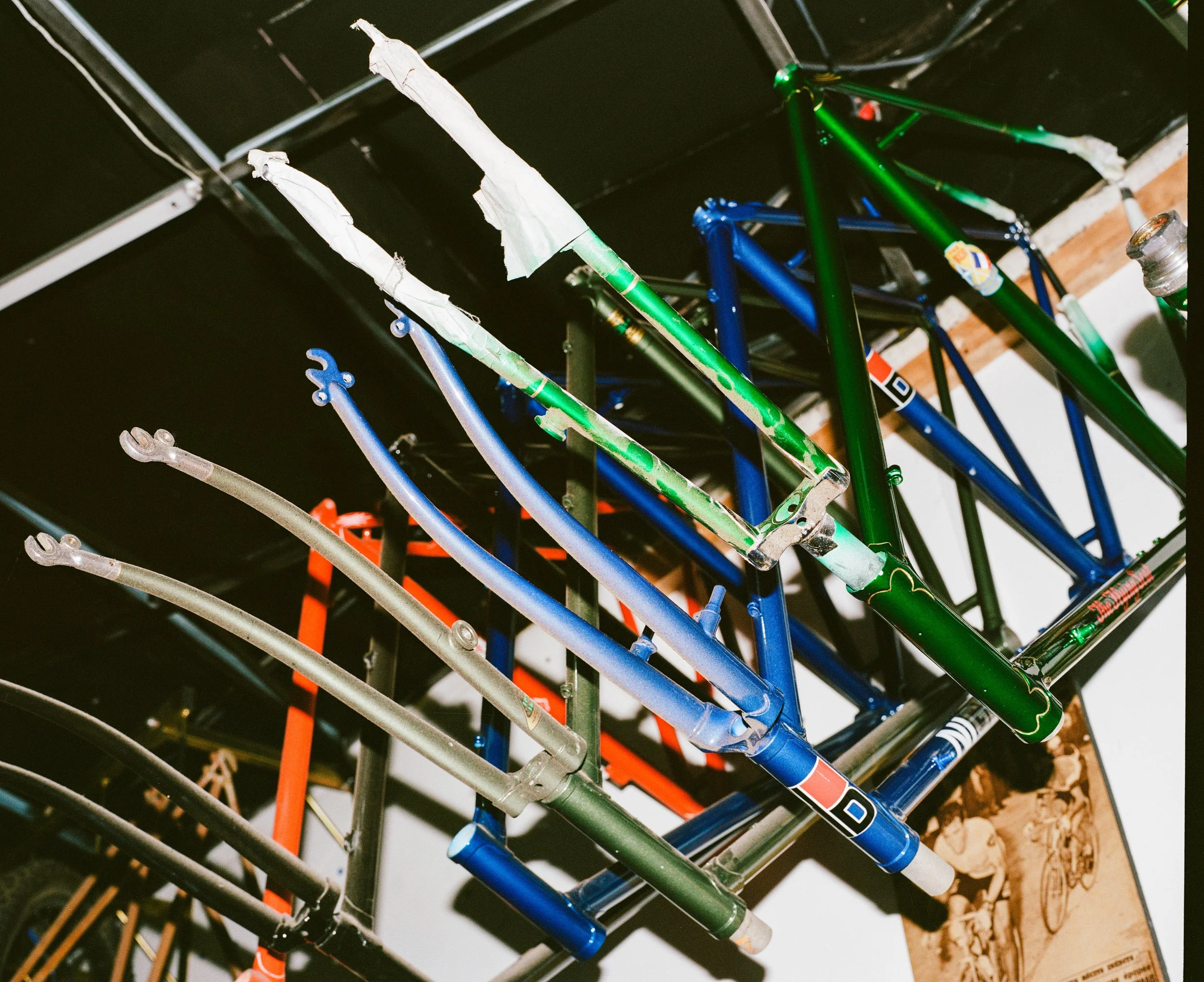 Colorful bicycle frames hanging on a rack in a bike shop.