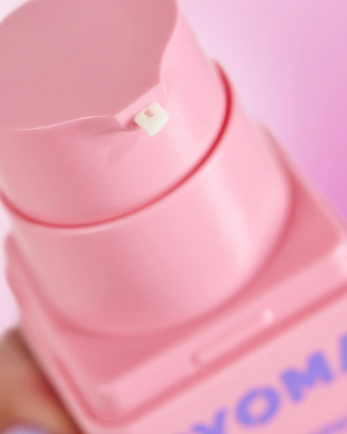 Close-up of stacked pink Byoma skincare product packaging, macro detail shot emphasizing smooth texture and soft pastel branding on a matching pink background