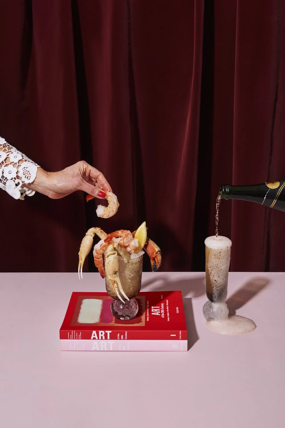 Hand in a pink glove placing or lifting a small product or confection on a dark red surface, moody close-up commercial shot with dramatic directional lighting