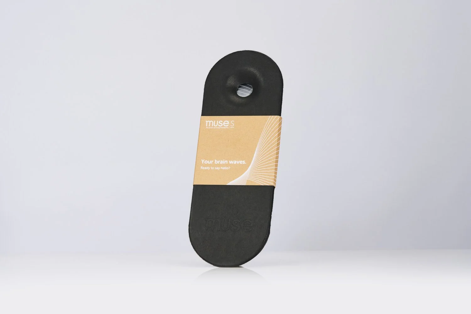 Standalone black oval wearable tech device on a clean white background, minimalist product photography with soft shadow and even studio lighting from above