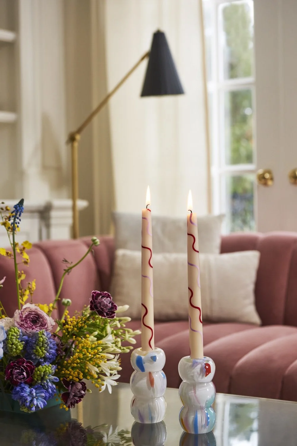 Moody interior dining scene with taper candles, fresh flowers, and warm pendant lighting, lifestyle atmosphere shot capturing an elegant and intimate table setting