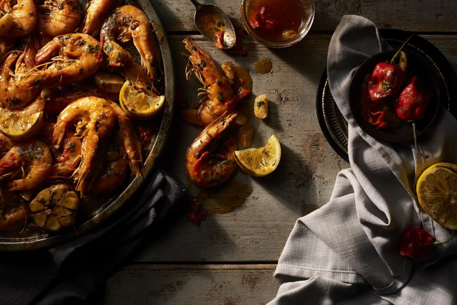 Dark moody overhead shot of golden fried shrimp piled on parchment paper on a well-worn wooden surface