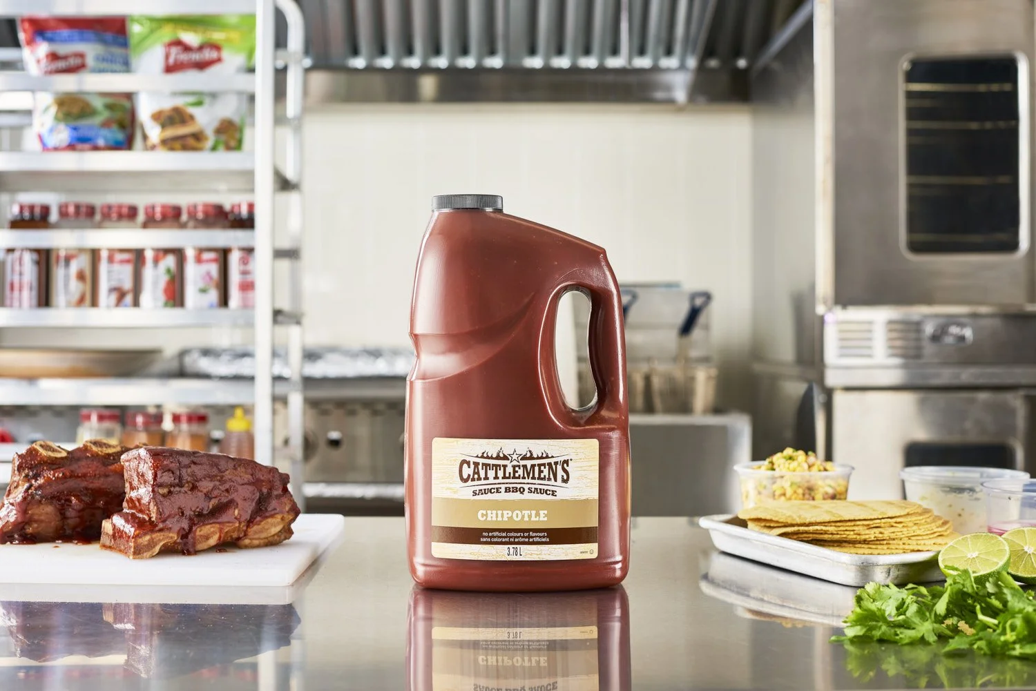Large jug of Cattleman's barbecue sauce standing in a bright modern kitchen surrounded by branded food products, appliances, and fresh ingredients, lifestyle commercial shoot with natural light