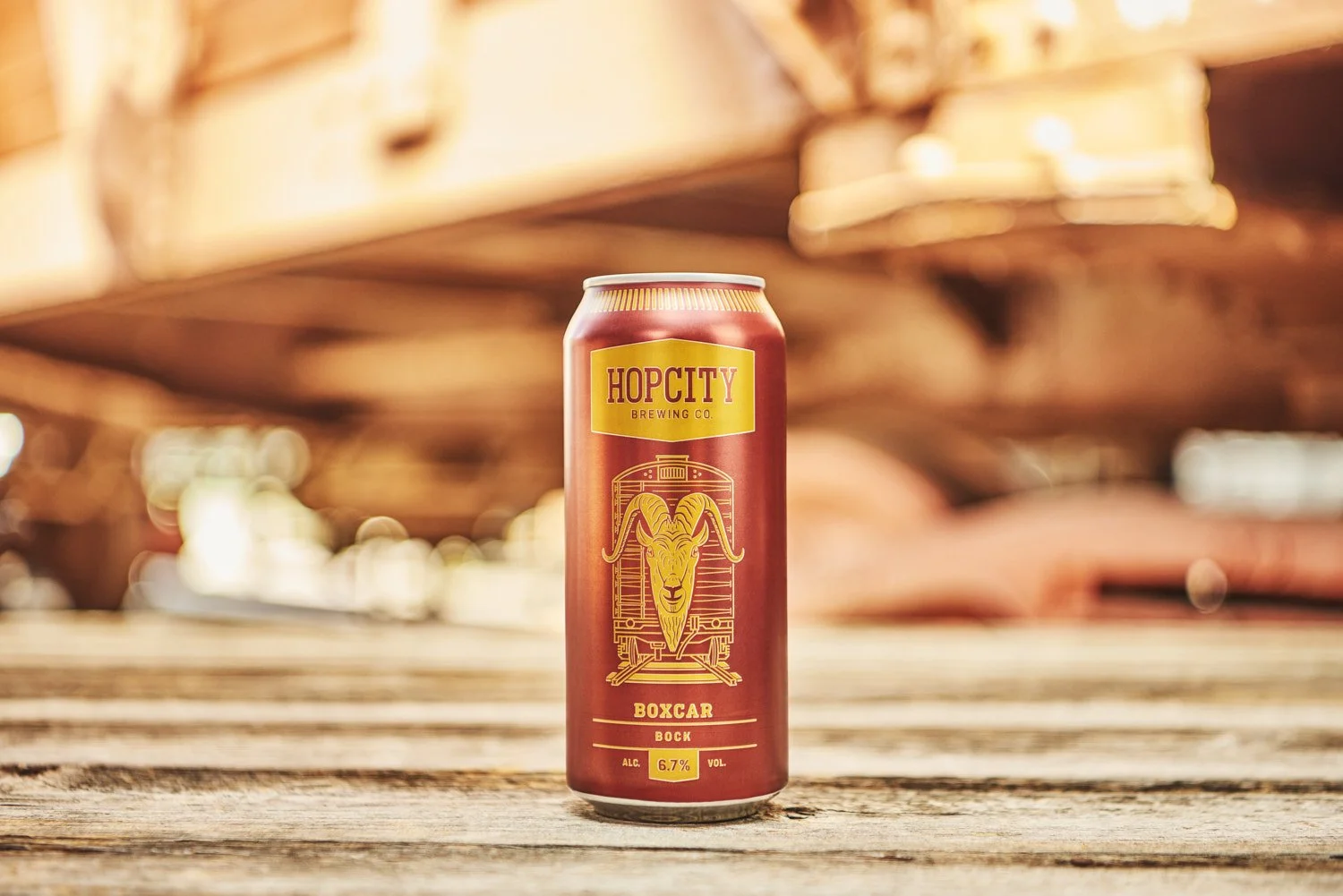 Branded beverage can resting against stacked pieces of rustic wood or lumber, warm lifestyle product shot with natural textured background and golden light