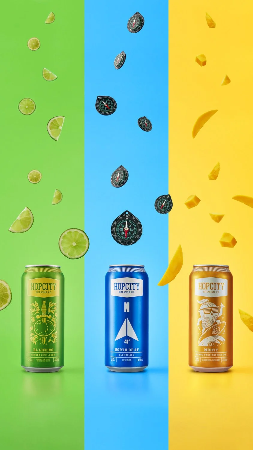 Three branded canned beverages in different flavors lined up on a split bold background of green, blue, and yellow, clean commercial product lineup shot