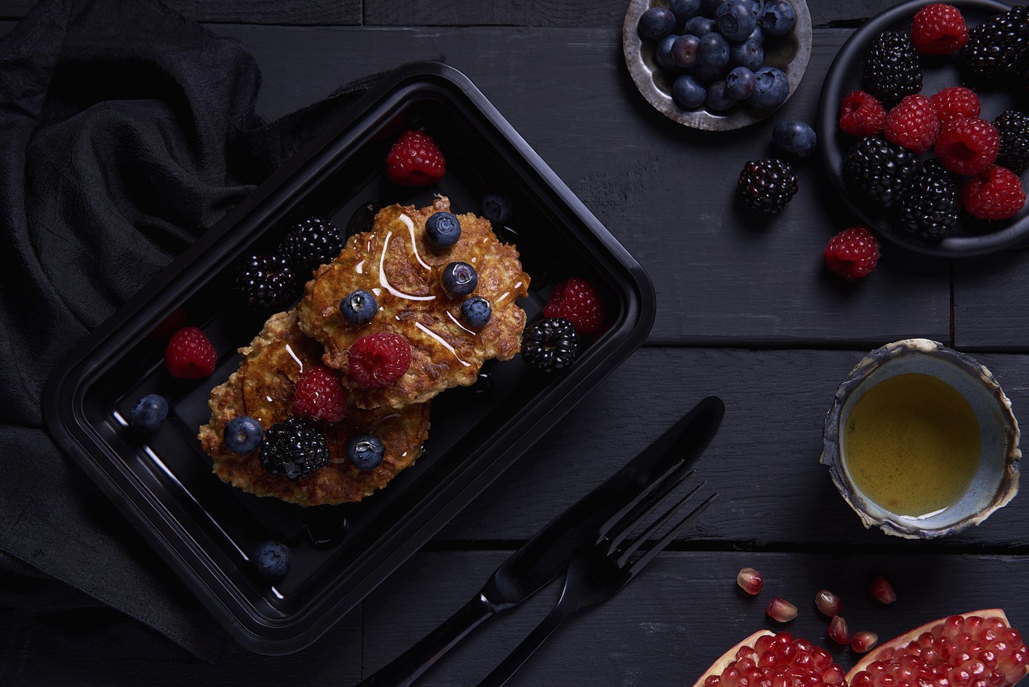  Grilled salmon fillet on a dark baking pan with scattered fresh berries, roasted vegetables, and olive oil drizzle, shot from directly above with even lighting