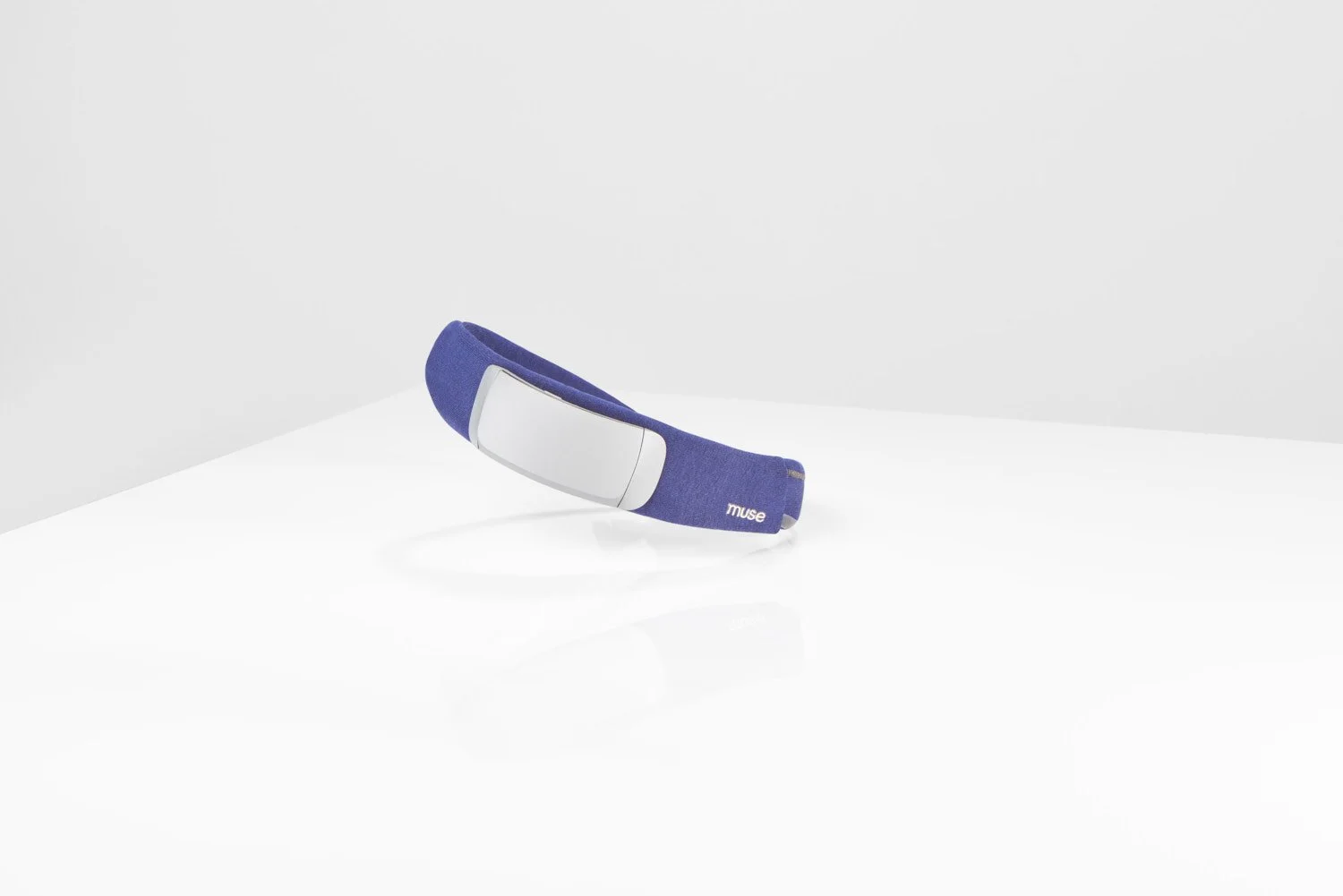 Single purple and grey wearable tech headband lying flat on a clean white background, minimal product shot with soft diffused studio lighting and clean shadow