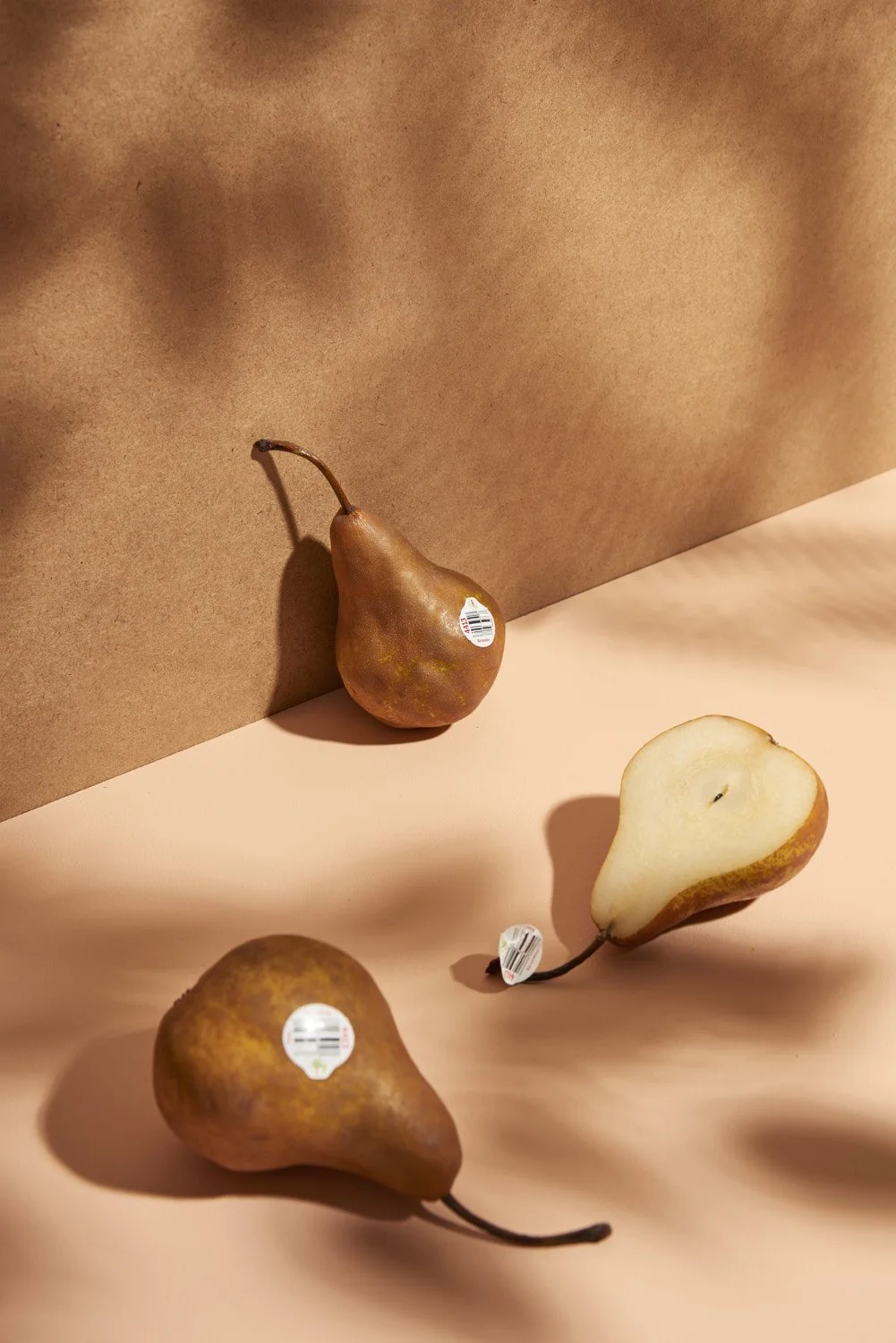 Two small ripe golden pears resting together on a draped piece of soft tan fabric, minimal and elegant food styling with gentle natural light from the side
