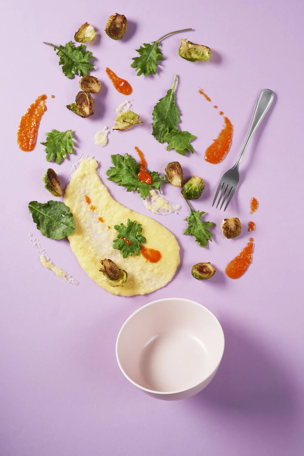Deconstructed creamy soup or curry with fresh vegetables, herbs, and garnishes floating artfully around a white bowl, shot on a soft lavender purple background