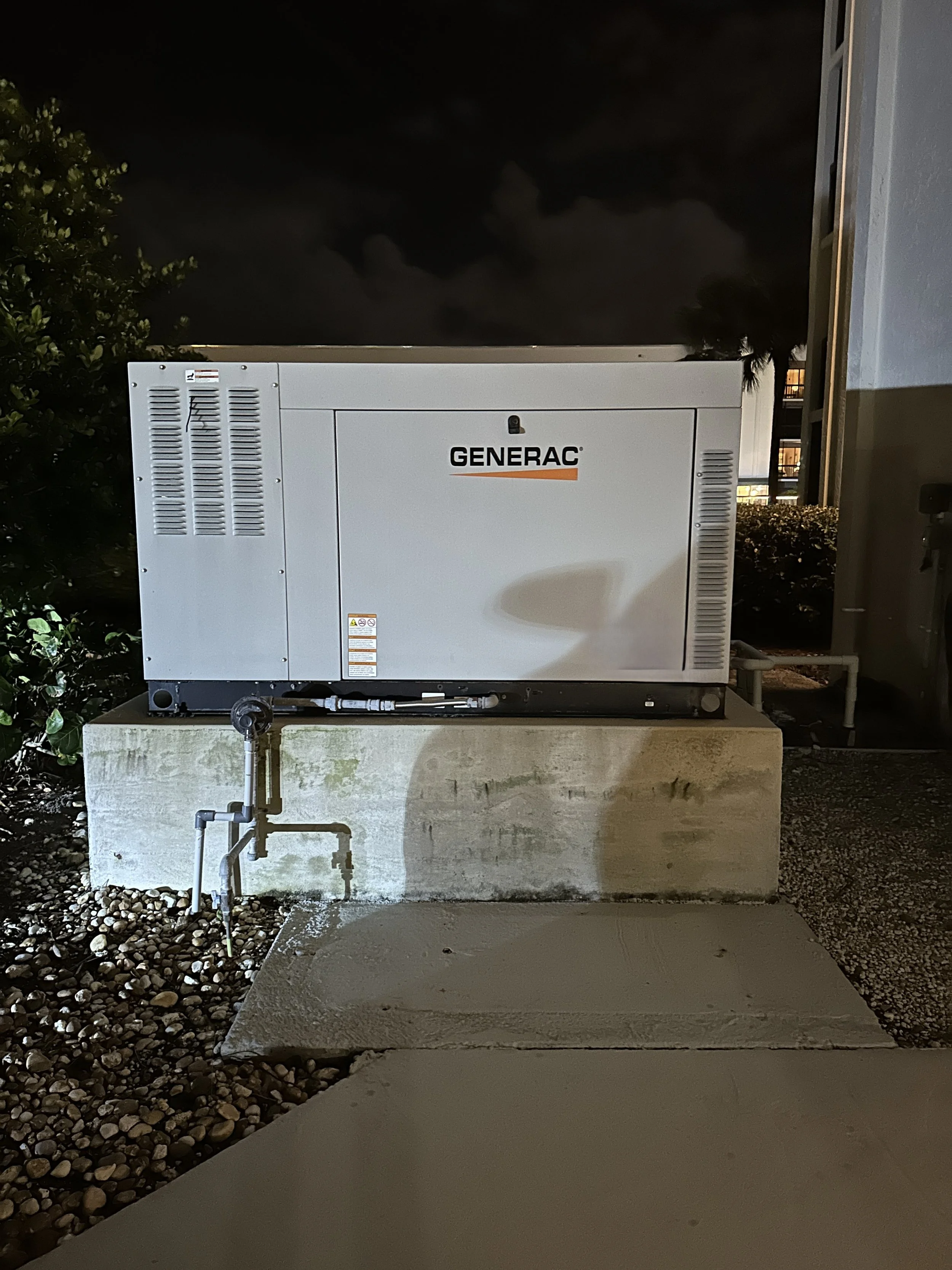 A Generac Commercial standby generator on a concrete platform outdoors. Jensen Beach Florida