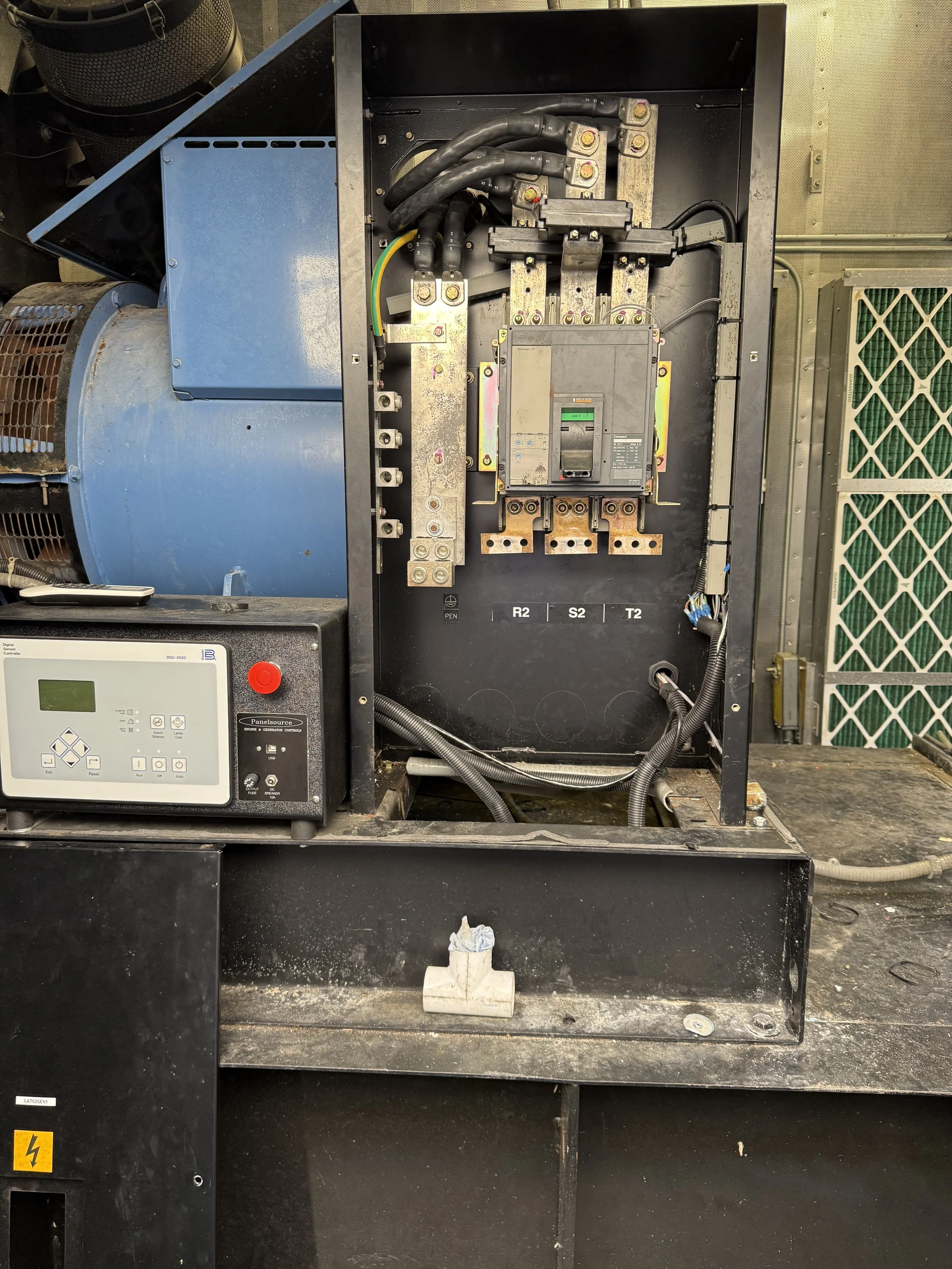 Open electrical panel with circuit breaker, wiring, and motor component inside a black metal enclosure.