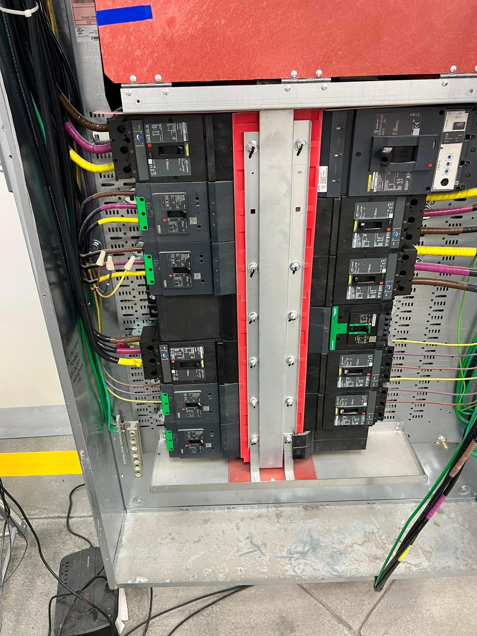 An electric service panel with circuit breakers and wiring inside a metal box.