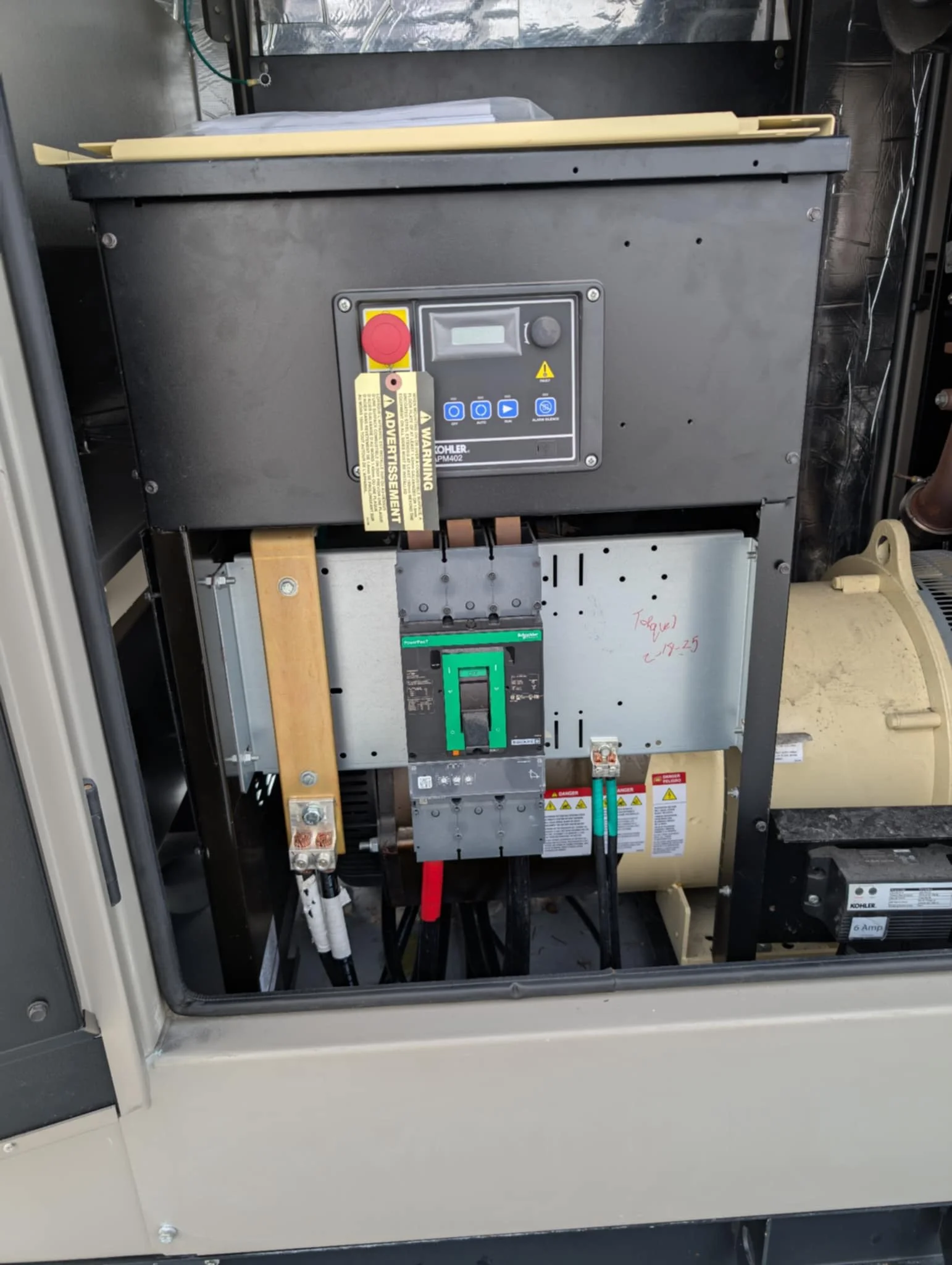 Close-up of an industrial machine with control panel, warning labels, and electrical components.