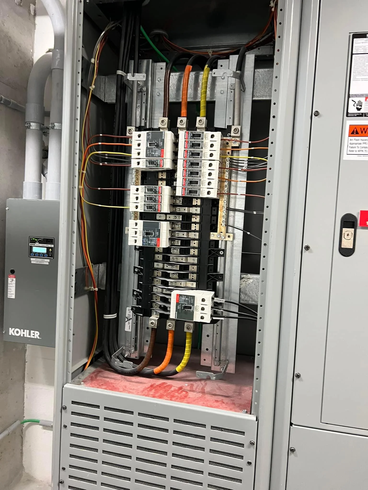 An electrical panel with circuit breakers and wiring inside a metal enclosure.