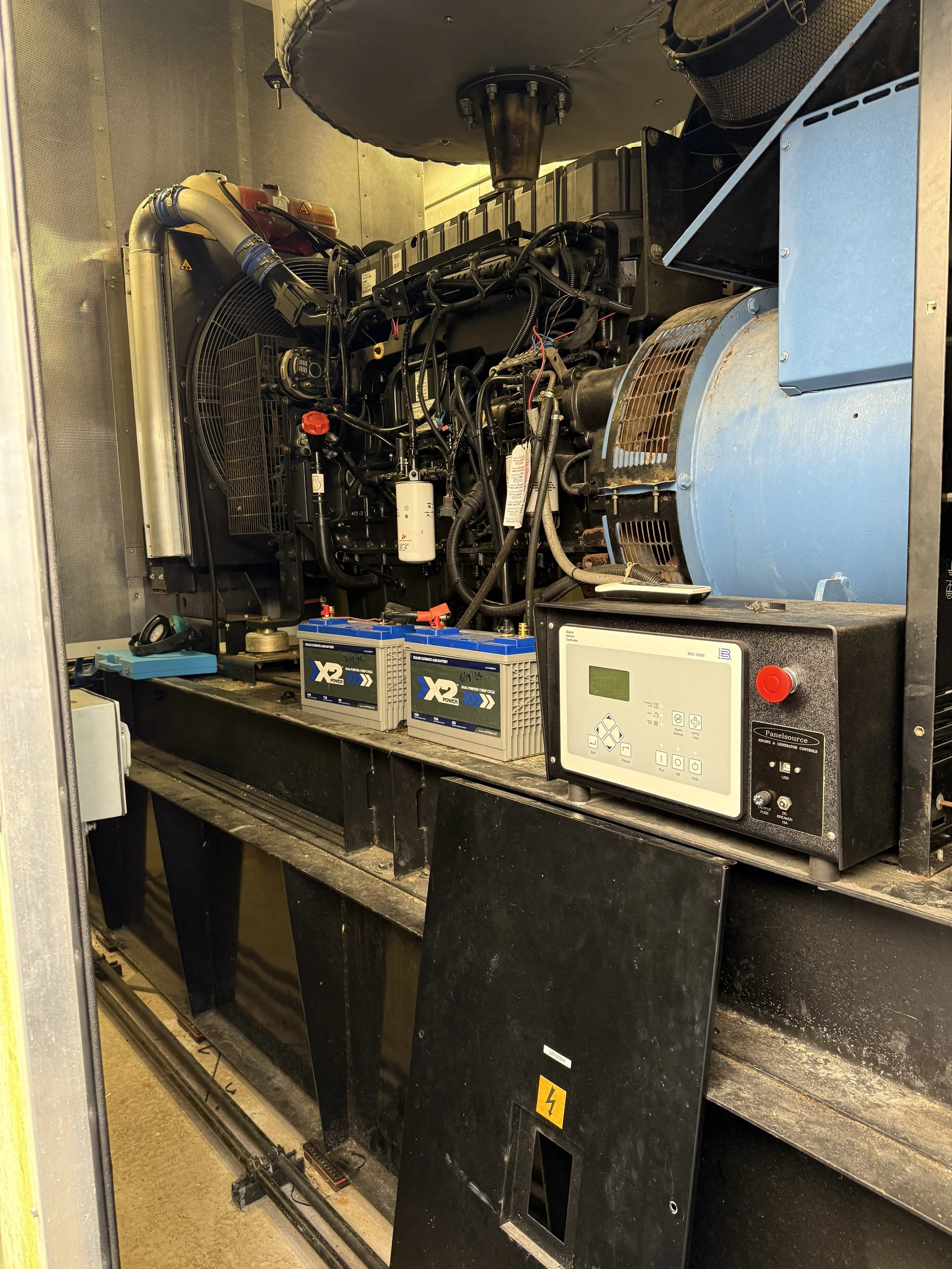 Inside view of an industrial generator with batteries, control panel, and engine components.