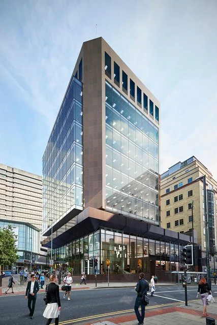 Former Lloyds Bank Building on a city street corner of Leeds with people walking.