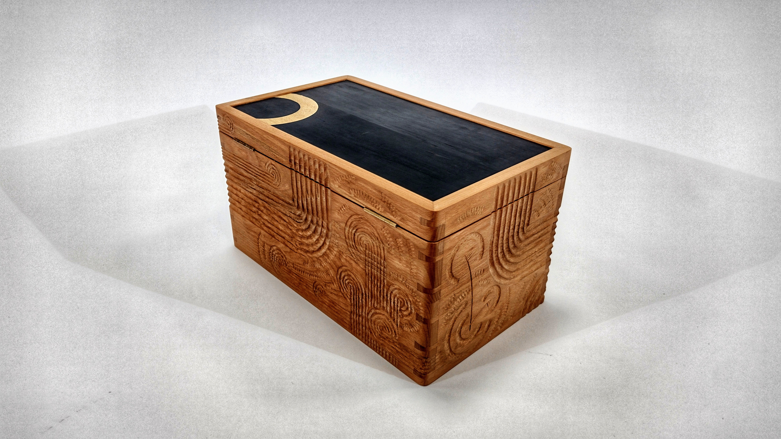Bespoke wooden box Oxford, hand-carved relief box, luxury handcrafted furniture UK, Polynesian-inspired carving, Mesoamerican art influence, custom art box, British studio furniture maker, Ellis James Stacey bespoke furniture.