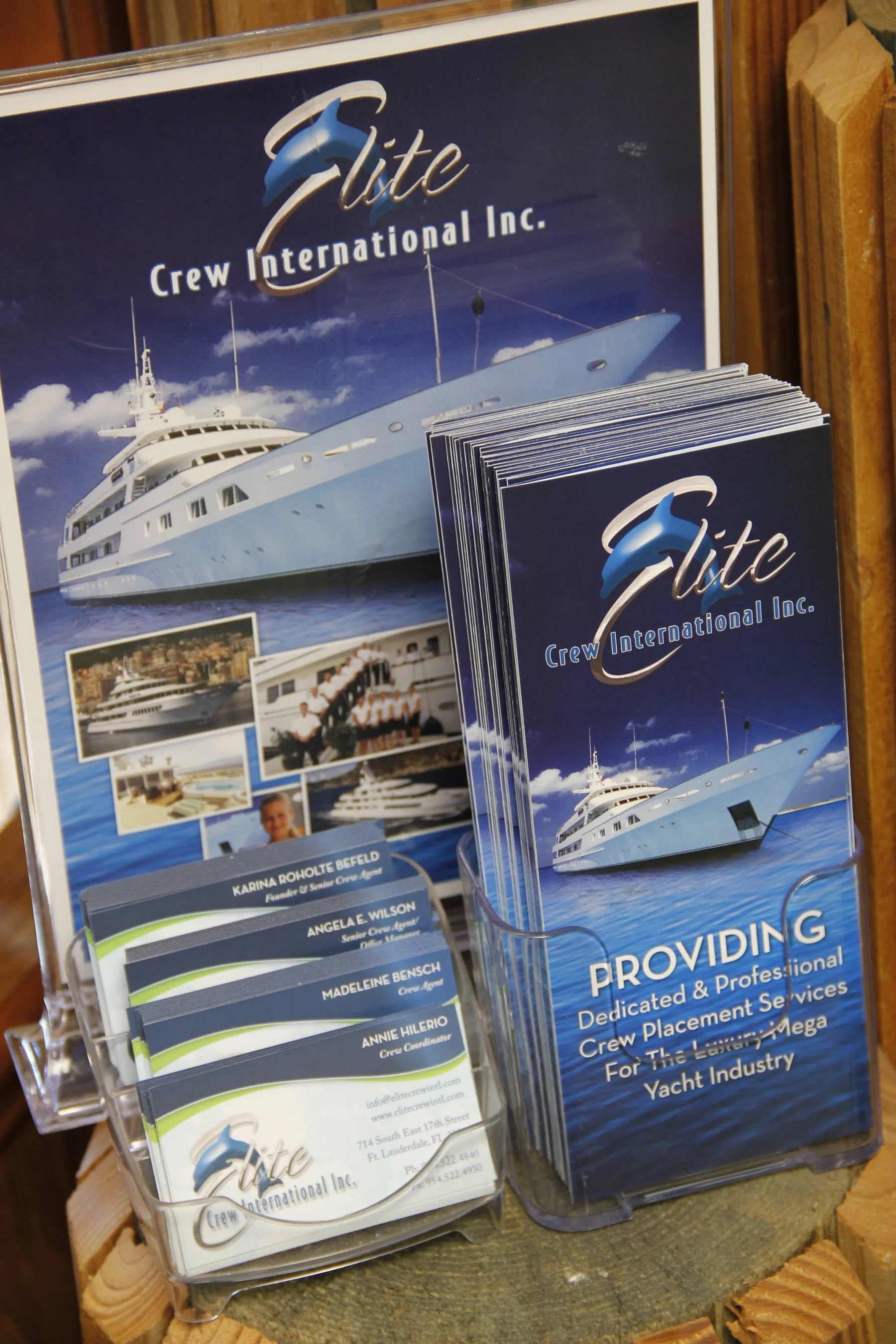 Brochures and business cards for Elite Crew International displayed on a stand, featuring a mega yacht image.