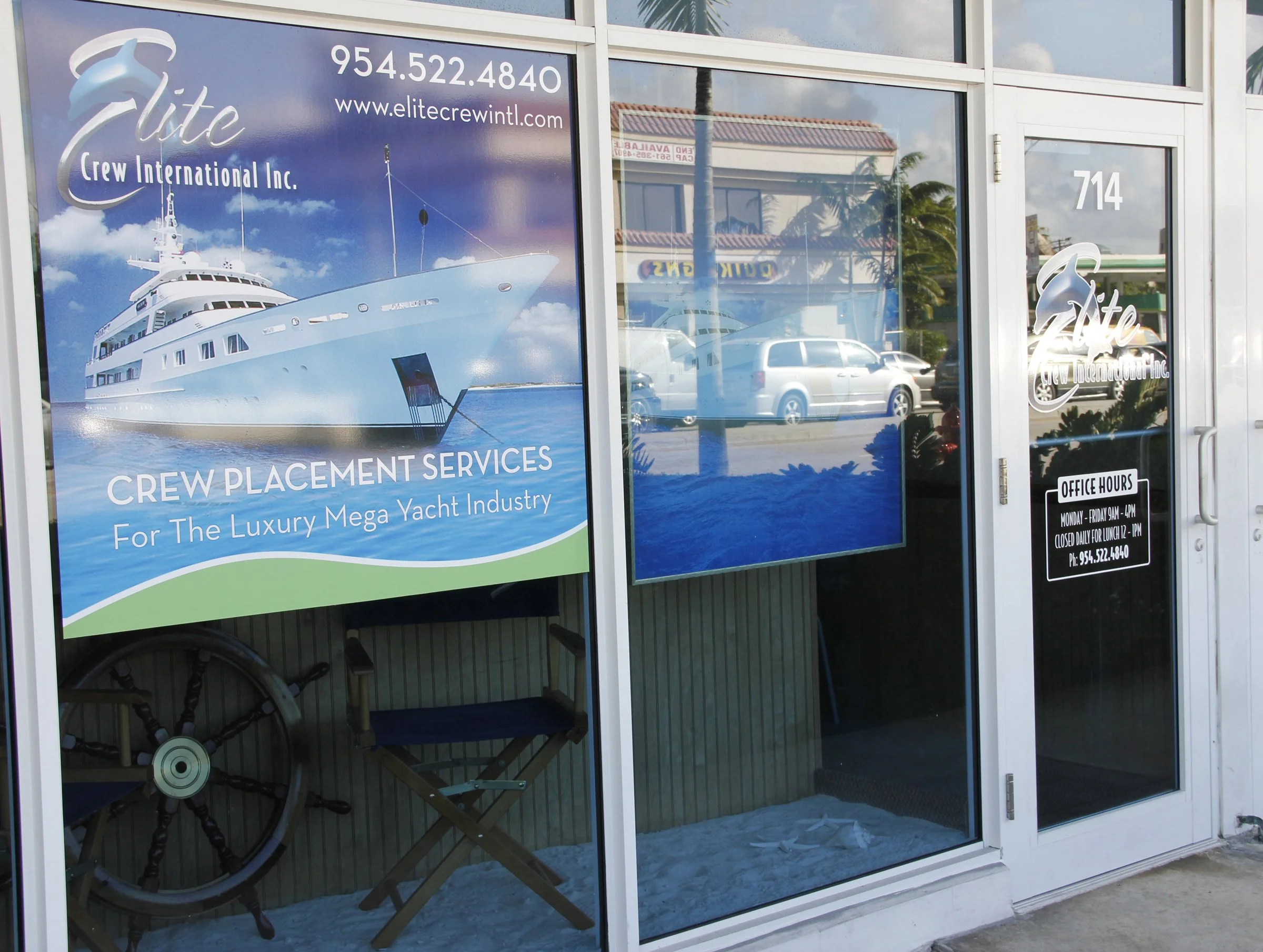 Entrance of Elite Crew International Inc. with sign advertising luxury mega yacht crew placement services, featuring a yacht image and office information on door.