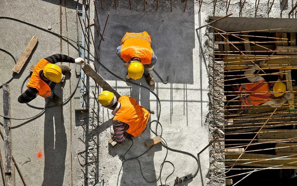Construction workers in safety vests and hard hats working on a concrete site