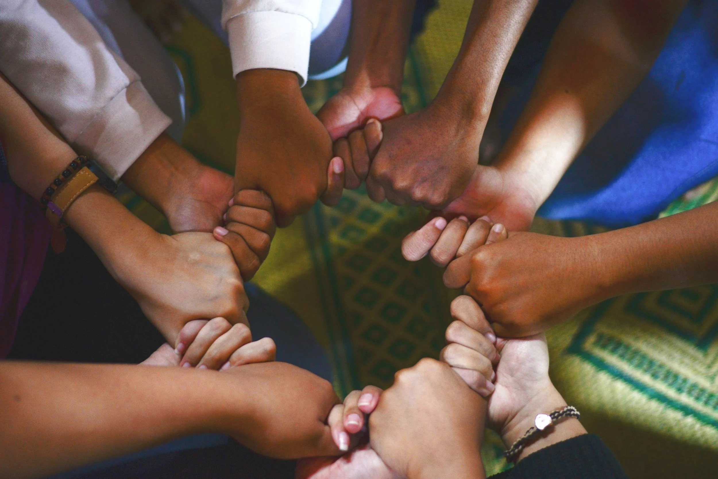 A group of diverse hands joining together in a circle, symbolizing unity and teamwork.