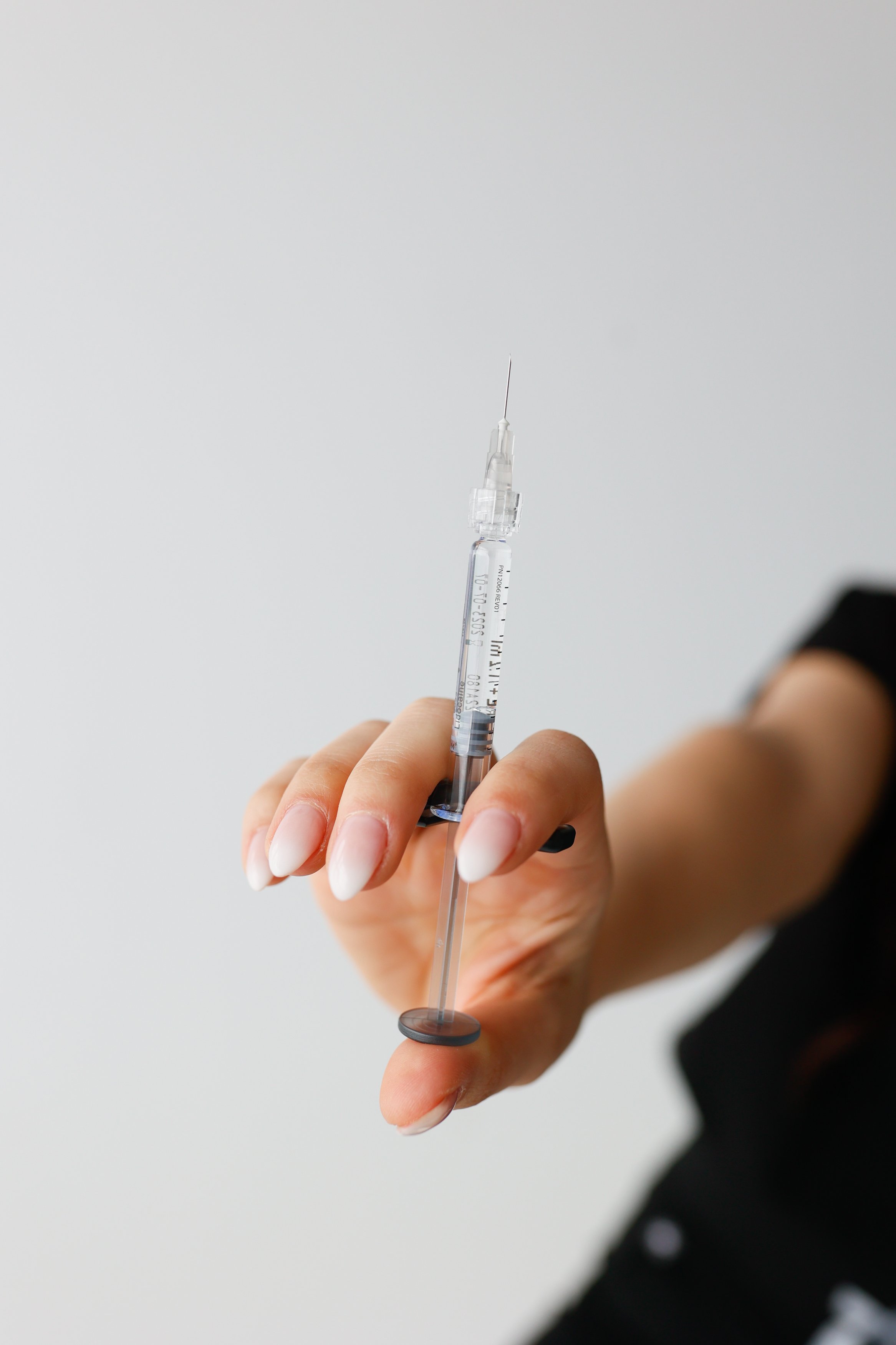 Licensed Nurse Practitioner Cassie Cimino holding a needle up to the camera in preparation to perform Botox injections with a client at Contour Medical Aesthetics & Wellness in St. Catharines