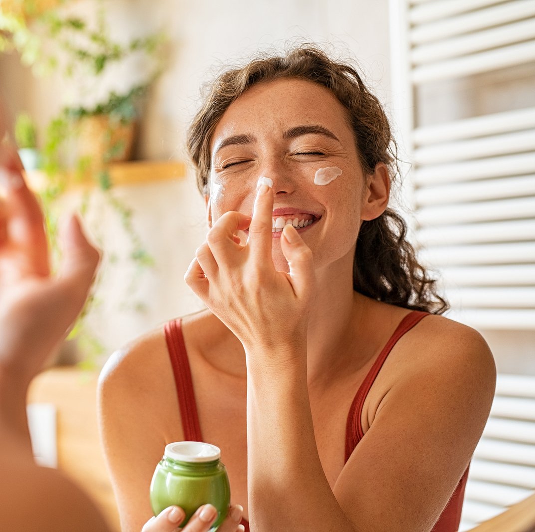 Young woman applying cream to her face