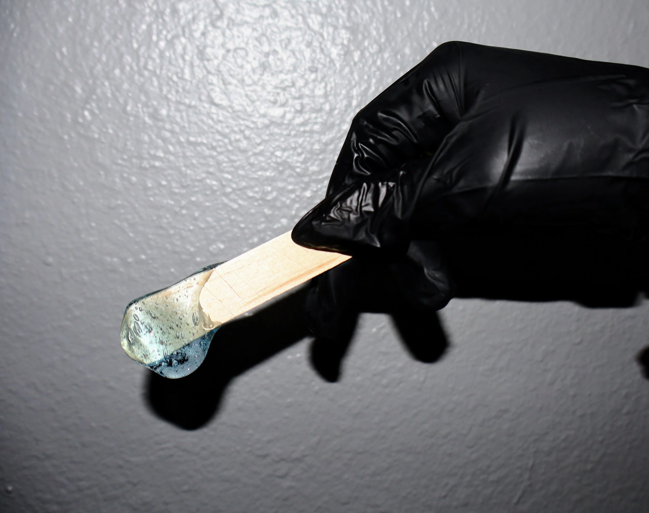 A wax applicator with light blue wax dripping off