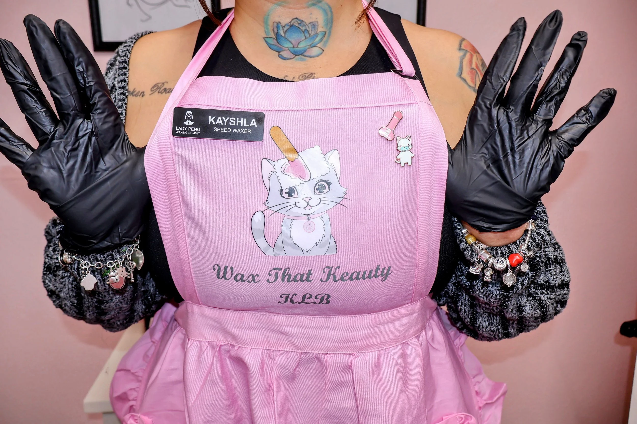 Kay wearing a pink apron that reads, "Wax that keauty, KLB"