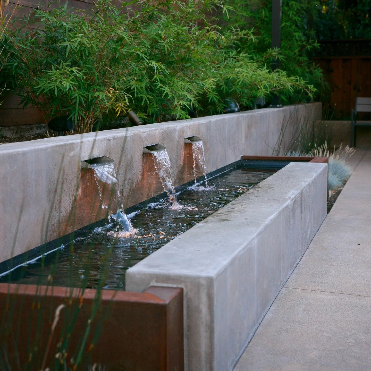 Rust. Stone. Green. Flow. 🔁 

The sound reaches you before the view does. A linear water feature where corten steel meets board-formed concrete all anchored by a dense bamboo planting. Water features that pull together the whole material palette are