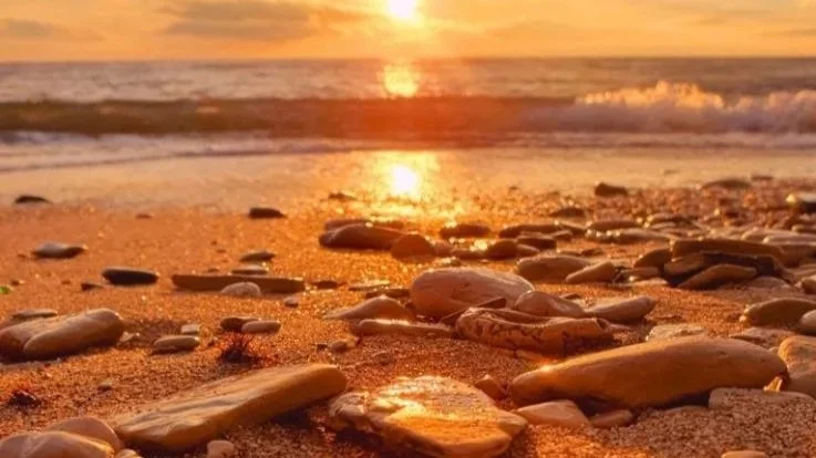 Sunrise over smooth beach stones at the summer solstice