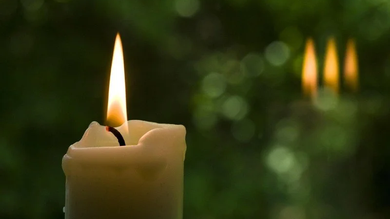 A lit candle against a soft green background, used for a summer solstice ritual