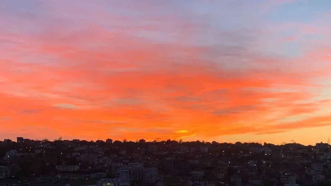 Soft pink and orange sunset over a city skyline, symbolising restoration, inner balance, and the natural return to harmony.