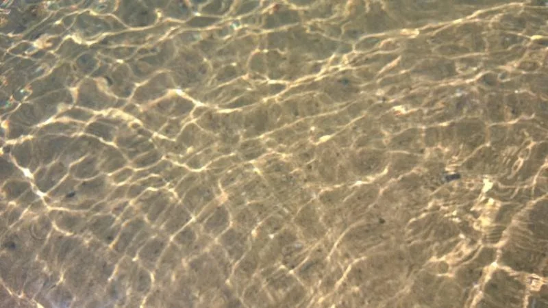Sunlight creating rippling patterns on clear water, symbolising the flow and interconnectedness of Reiki energy.