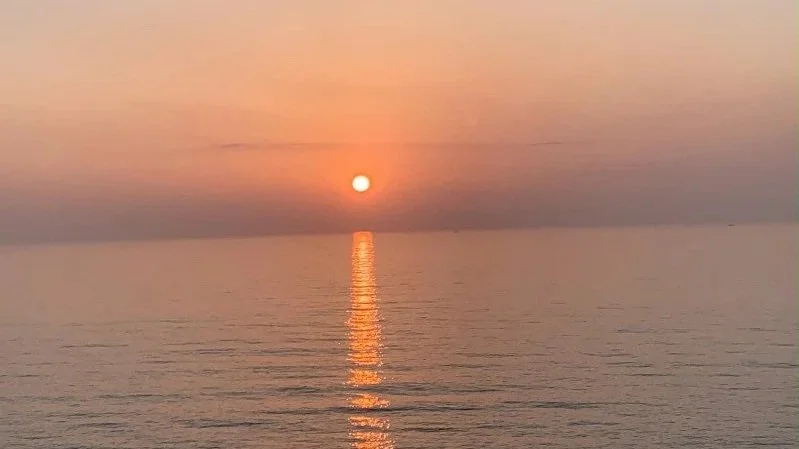 Sun setting over still water, representing Fire element energy at the summer solstice