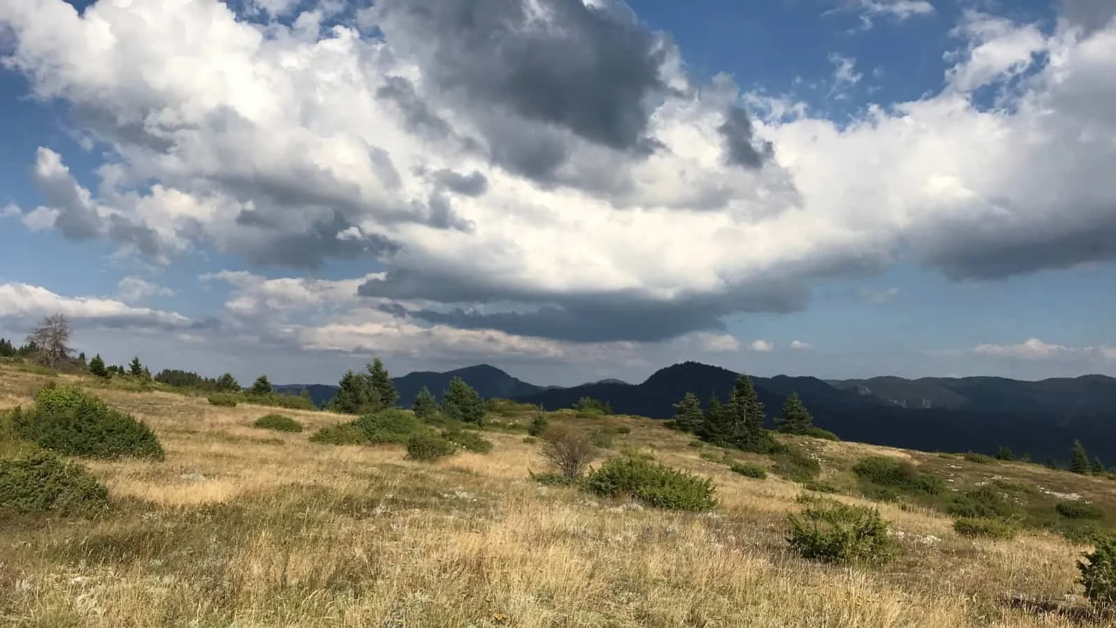 Wide mountain landscape beneath an open sky filled with clouds
