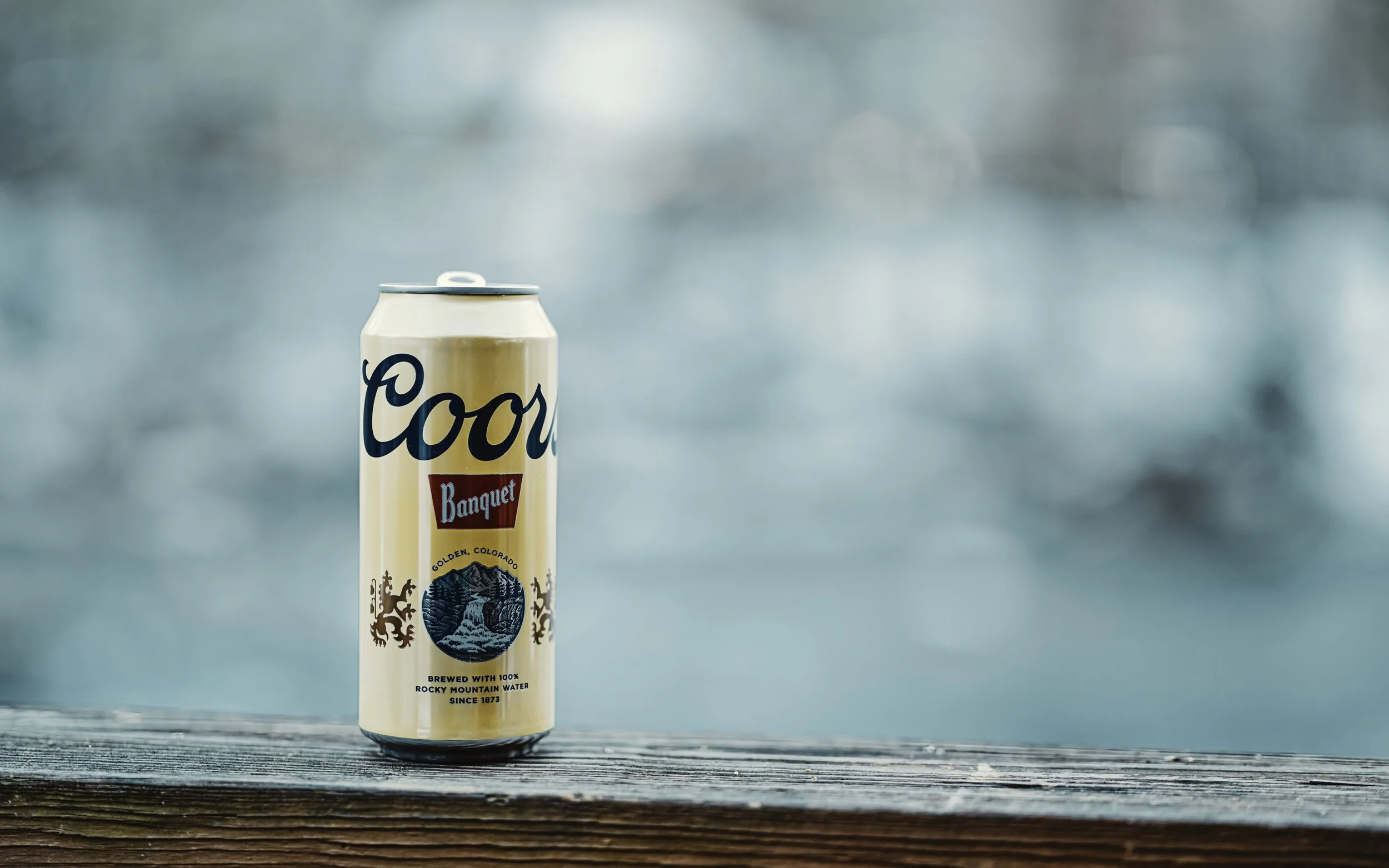 A can of Coors Banquet beer on a wooden fence with the Little River in the background.  Townsend, Tennessee