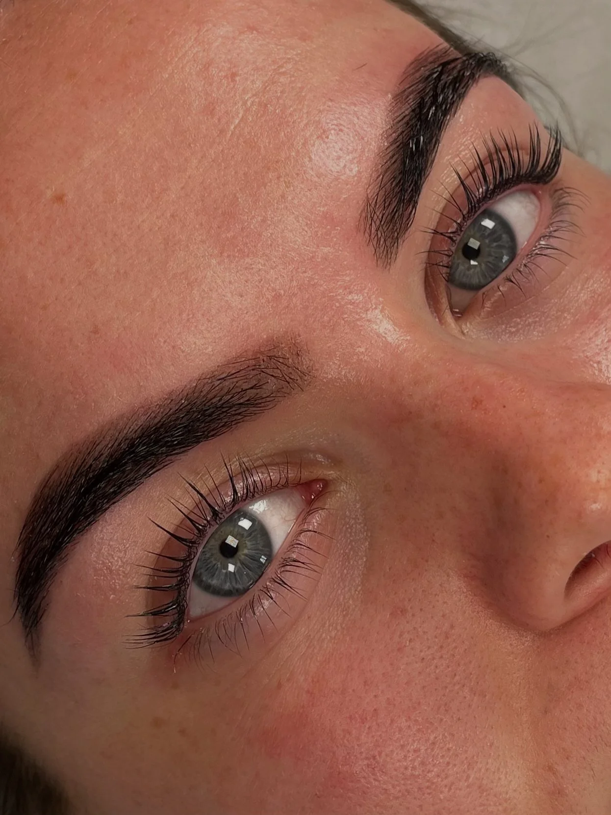 Close-up of a person's face focusing on the eyes, showcasing well-groomed eyebrows and long eyelashes.