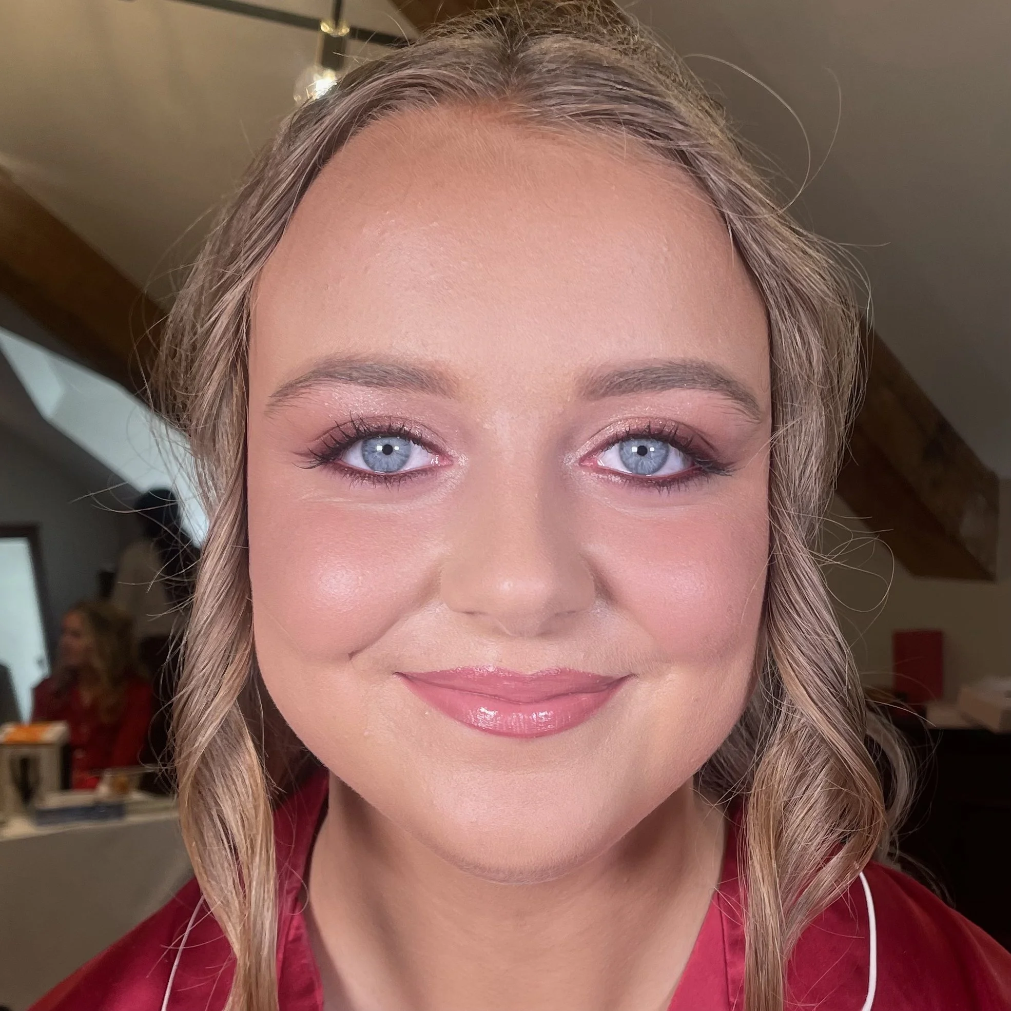 Close-up of a young woman with blonde hair, blue eyes, makeup, and a gentle smile.