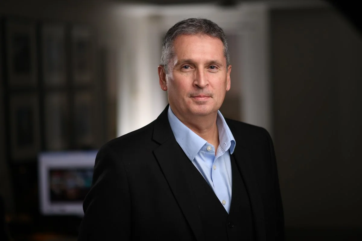 Corporate headshot of Larry Crane, ACHA, AIA, NCARB, LEED AP. He is wearing a blue oxford shirt with a black suit jacket.
