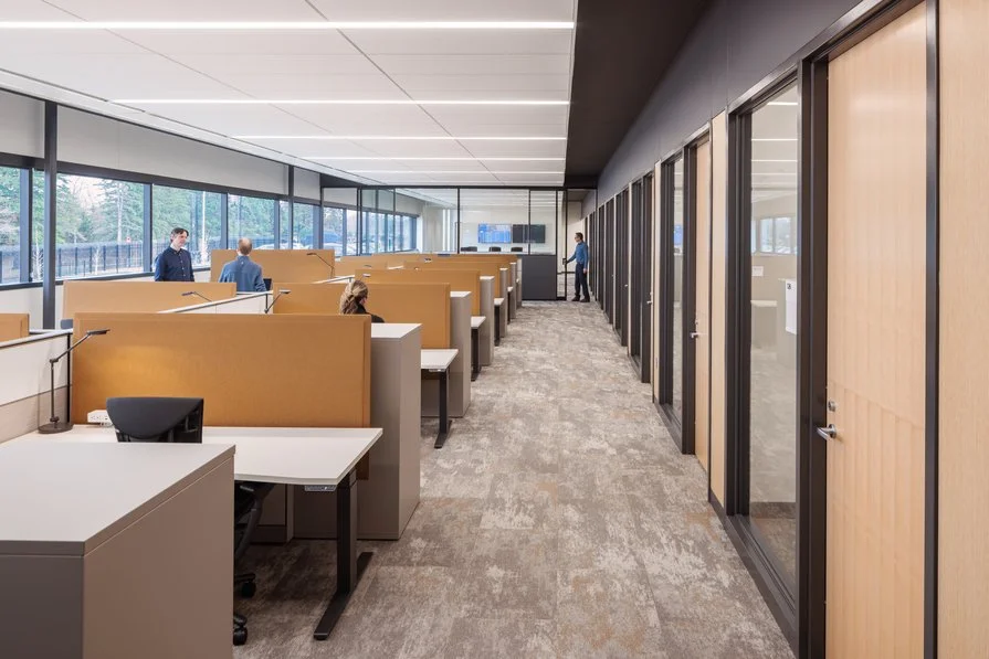 Workstations in open office environment positioned with access to windows with private offices situated opposite side of the curtain wall.