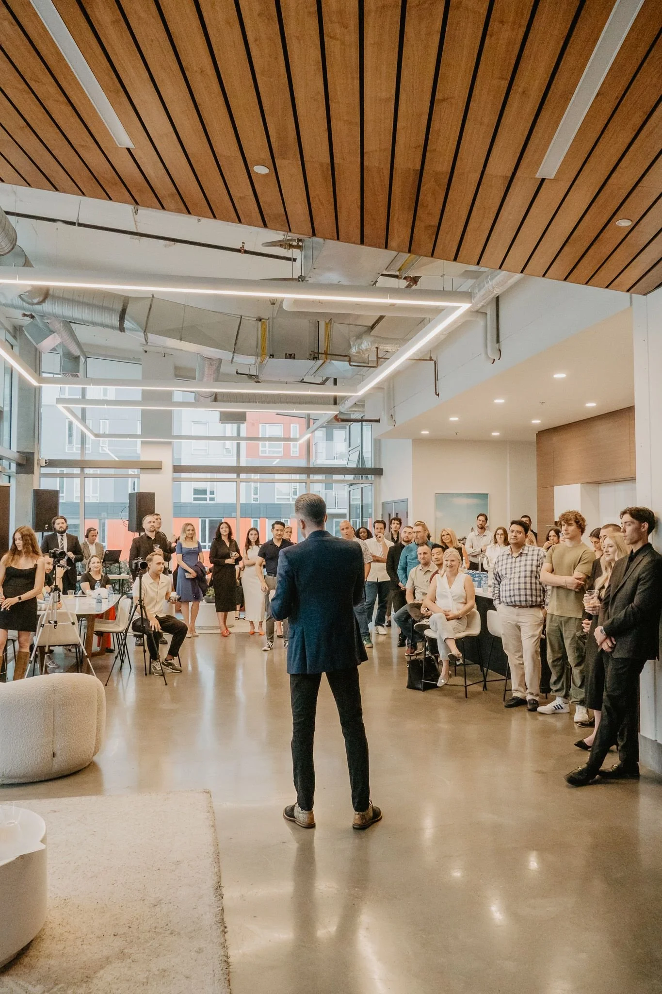 Rear view of a speaker presenting to a crowd during a corporate networking event captured by Aces and Oak. (