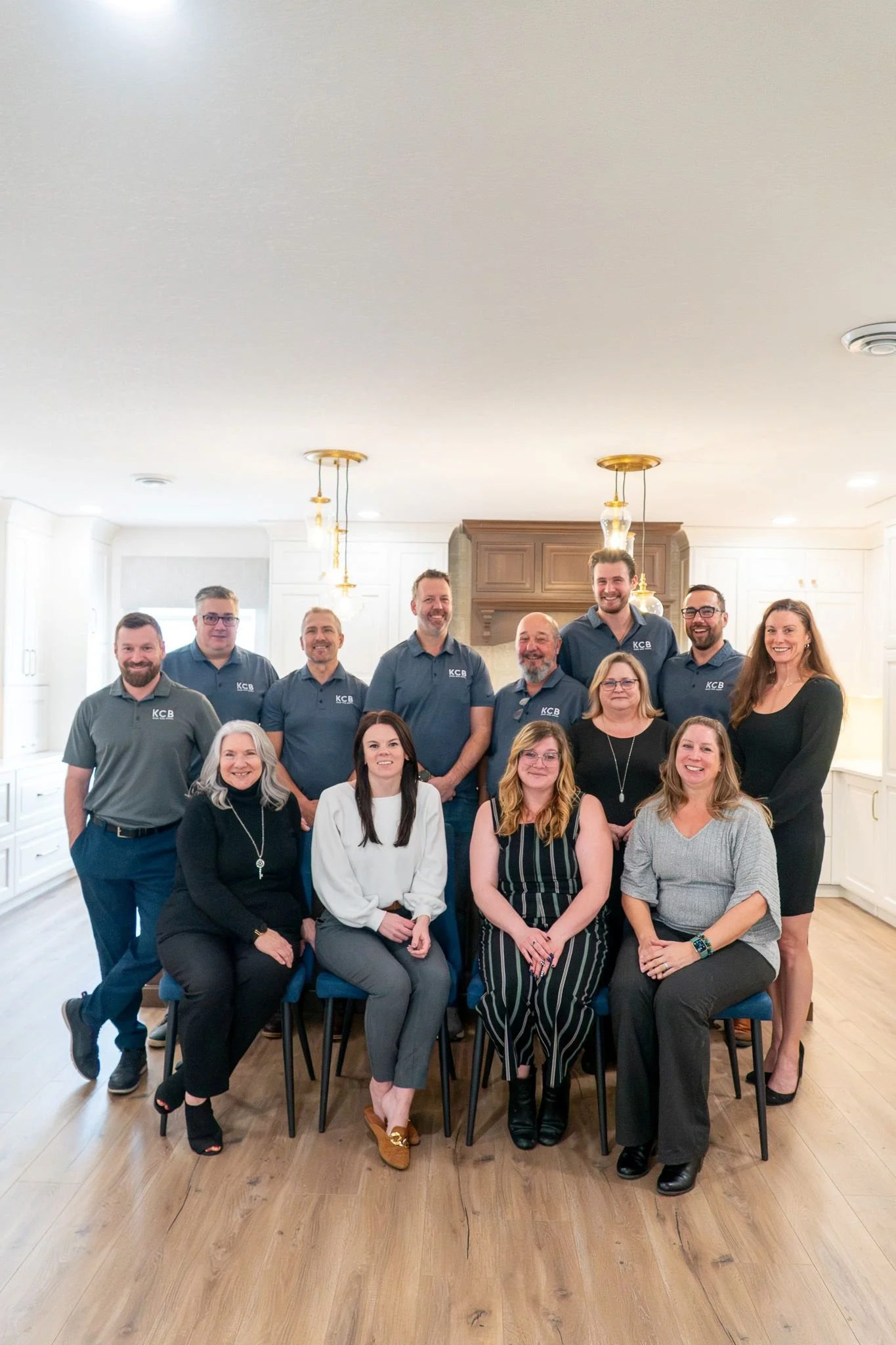 A professional corporate group portrait of the KCB team taken inside a bright, modern custom kitchen showcase during a brand photography session by Aces and Oak.