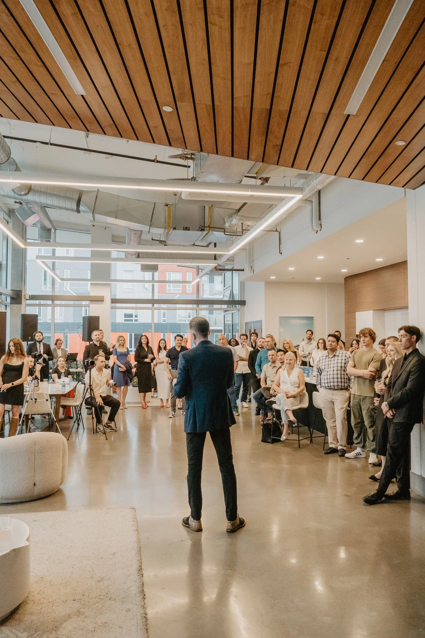 Rear view of a speaker presenting to a crowd during a corporate networking event captured by Aces and Oak.